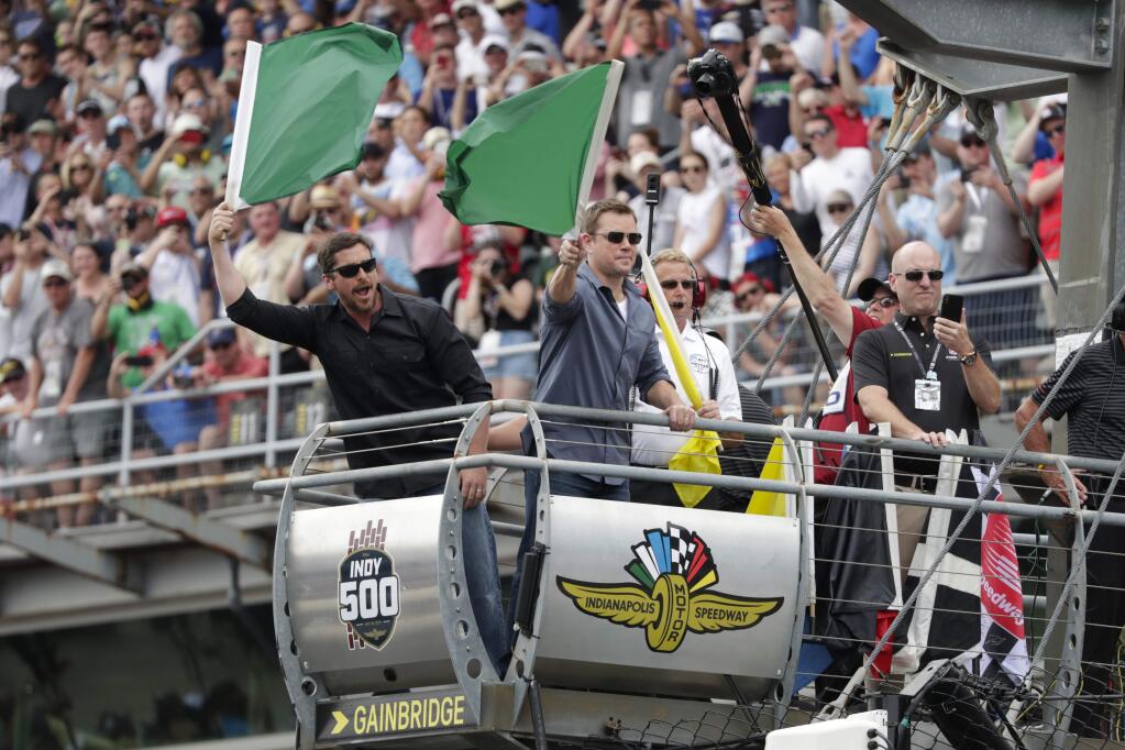 Actors Matt Damon, right, and Christian Bale wave green flags to start Indianapolis 500 IndyCar auto race at Indianapolis Motor Speedway, Sunday, May 26, 2019, in Indianapolis. (AP Photo/Michael Conroy)