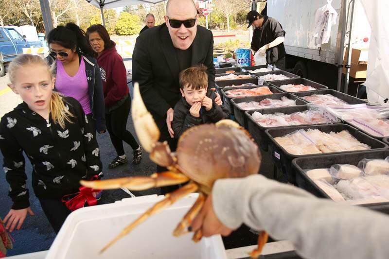 (File photo) Andy Meyer and his son Jack, center, react to seeing a live Dungeness crab being sold at the Windsor Farmers Market in the Town Green on Sunday, December 15, 2013. (Conner Jay/The Press Democrat)