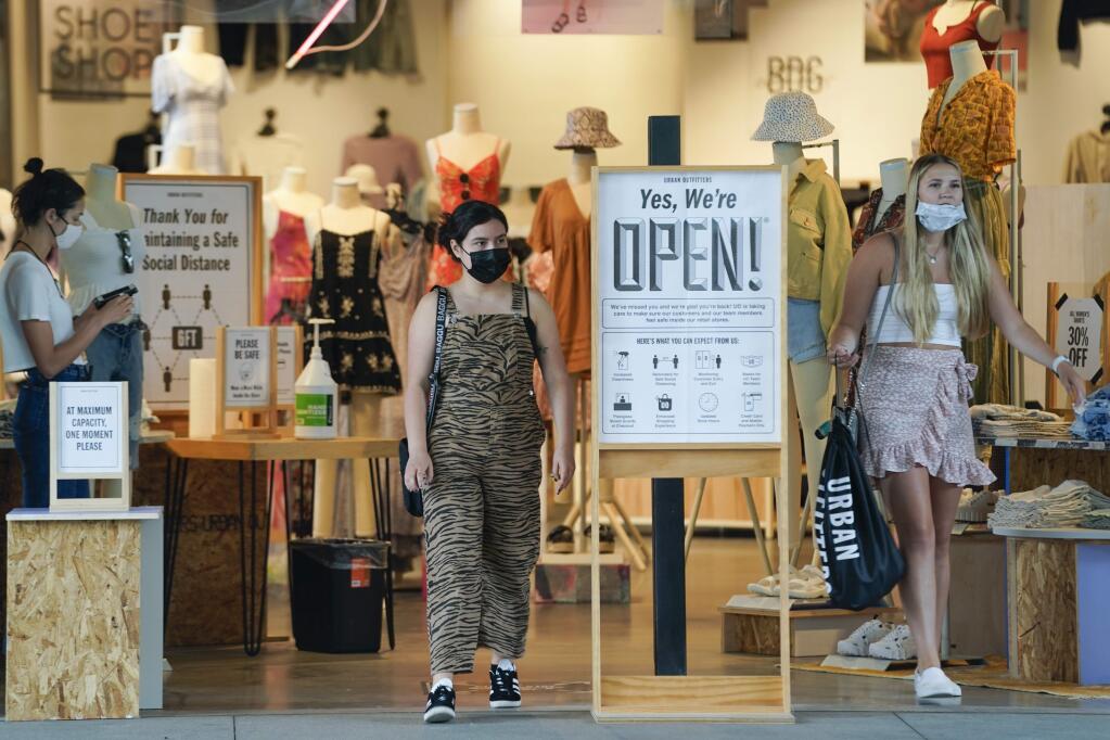 Customers leave Urban Outfitters with their purchases as they shop at Pacific City shopping mall on Tuesday, May 26, 2020, in Huntington Beach, Calif. (AP Photo/Ashley Landis)