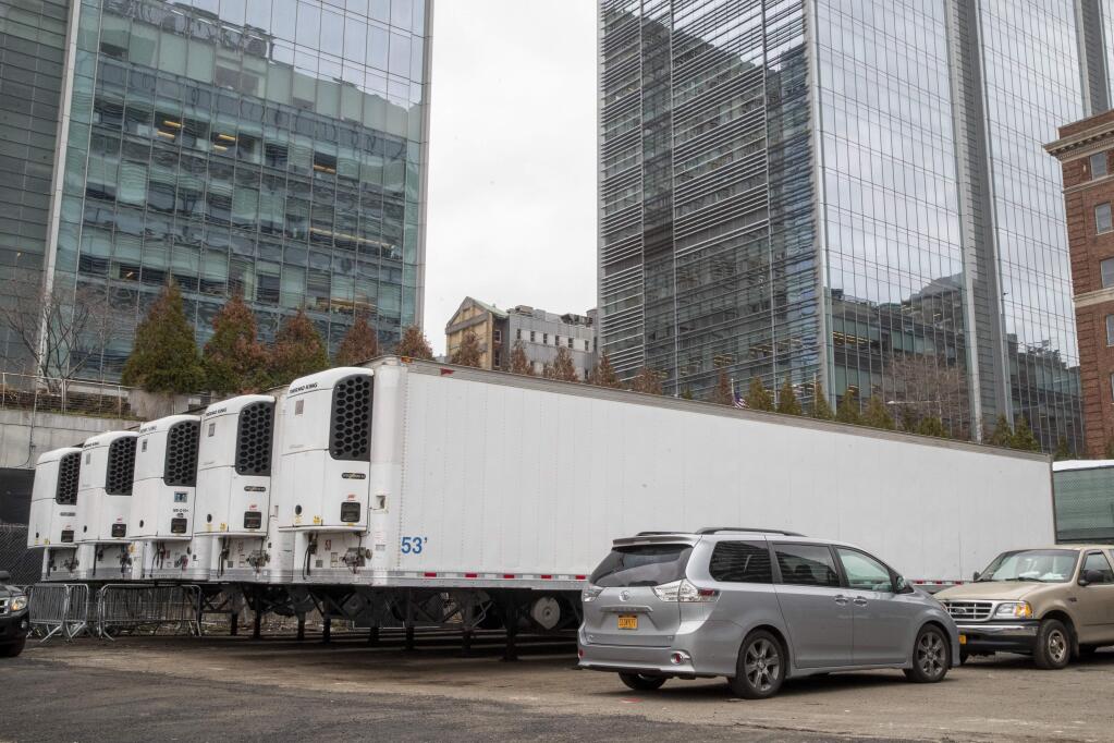 Refrigerated trailers are seen parked at the site of a makeshift morgue being built in New York, Wednesday, March 25, 2020. New York officials are keeping a close eye on already-stressed hospitals as the number of cases is projected to rise for perhaps three more weeks. The new coronavirus causes mild or moderate symptoms for most people, but for some, especially older adults and people with existing health problems, it can cause more severe illness or death. (AP Photo/Mary Altaffer)