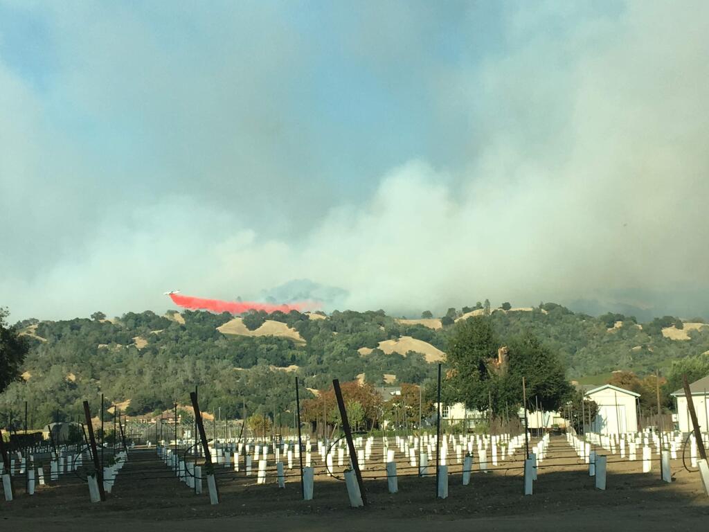 A plane drops flame retardant on the Pocket fire burning Wednesday in the Mayacamas Mountains east of Geyserville, Oct. 11. Seen from River Road north of Highway 128. (J.D. Morris/ The Press Democrat)