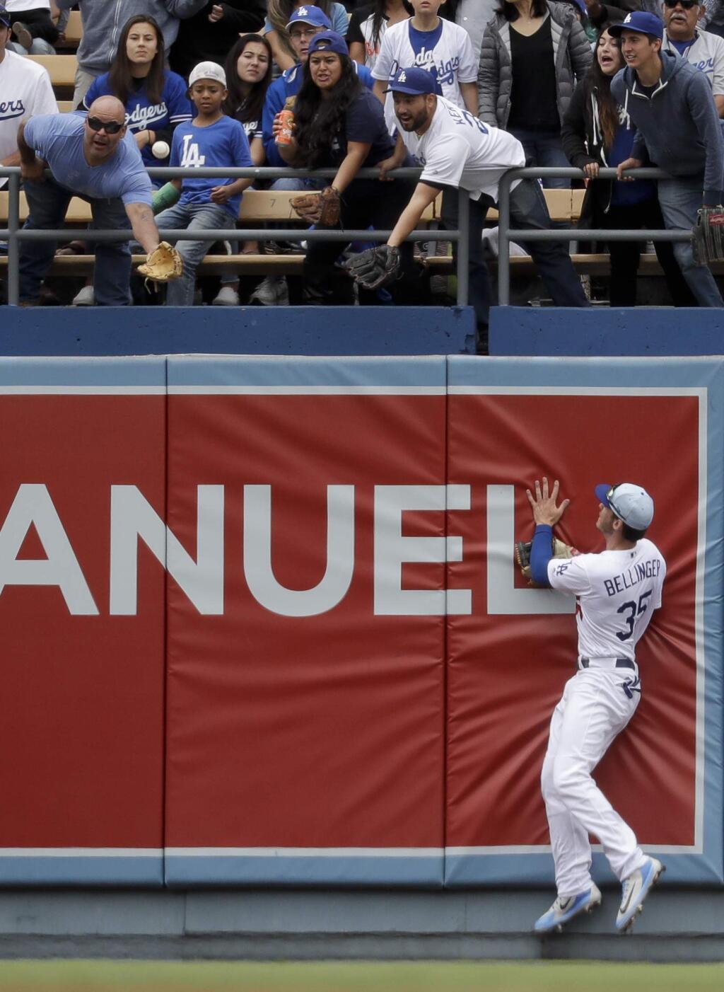 Fans try to catch a two-run home run ball hit by San Francisco Giants' Brandon Belt as Los Angeles Dodgers first baseman Cody Bellinger looks on during the third inning of a baseball game in Los Angeles, Sunday, June 17, 2018. (AP Photo/Chris Carlson)