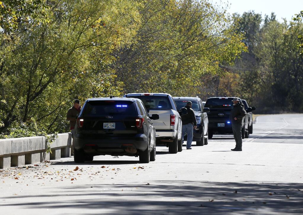 Officials investigate a bridge near the Deep Fork River where bodies were found in Okmulgee, Okla, on Monday, Oct. 17, 2022. (Stephen Pingry/Tulsa World via AP)
