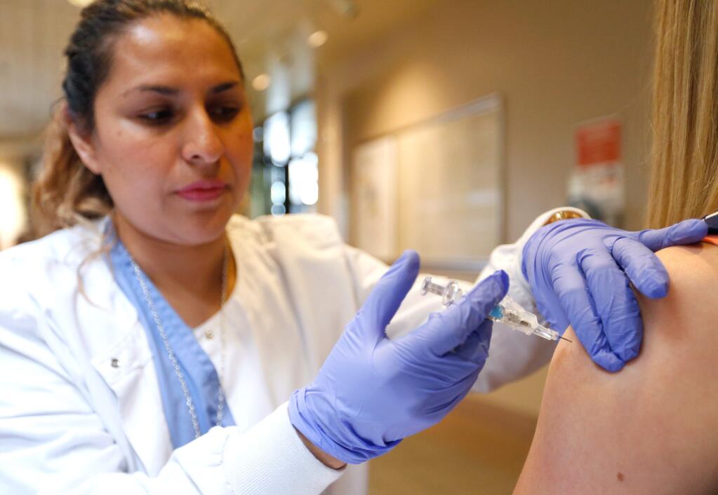 Licensed vocational nurse Karina Cortes gives a flu shot injection to Susan Schultz of Rohnert Park, at Kaiser Permanente in Santa Rosa, California on Tuesday, October 11, 2016. (Alvin Jornada / The Press Democrat)