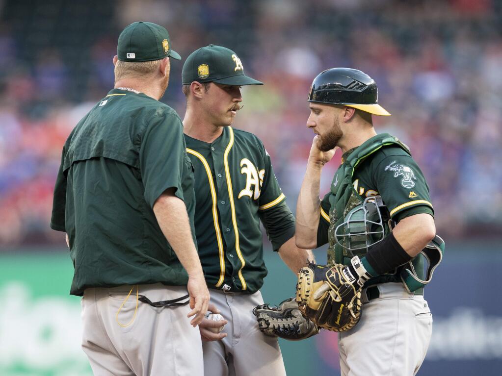 Oakland Athletics starting pitcher Daniel Mengden, middle, meets on the mound with pitching coach Scott Emerson, left, and catcher Jonathan Lucroy after giving up back-to-back home runs to the Texas Rangers during the first inning Wednesday, June 6, 2018, in Arlington, Texas. (AP Photo/Jim Cowsert)