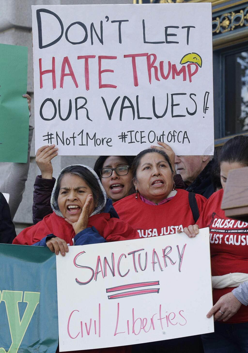 FILE - In this Jan. 25, 2017 file photo, protesters hold signs as they yell at a rally outside of City Hall in San Francisco. Immigration is one of the major issues between the California gubernatorial candidates in the election Tuesday, Nov. 6, 2018, for California governor. Republican candidate John Cox is opposed to California's 'sanctuary state' legislation, while Democratic candidate Gavin Newsom supports it and wants comprehensive immigration reform at the federal level and opposes building a wall on the U.S.-Mexico border. (AP Photo/Jeff Chiu, File)