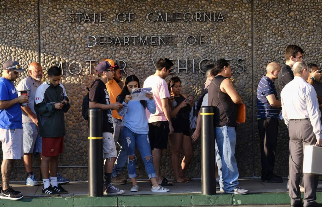 FILE - In this Aug. 7. 2018 file photo people line up at the California Department of Motor Vehicles prior to opening in the Van Nuys section of Los Angeles. Gov. Gavin Newsom released a report, Tuesday, July 23, 2019, detailing efforts by the DMV to improve customer service. Some of the suggestions are to accept credit cards, upgrade the DMV's website and offer clearer instructions on how to obtain a new federally mandated ID. (AP Photo/Richard Vogel, File)
