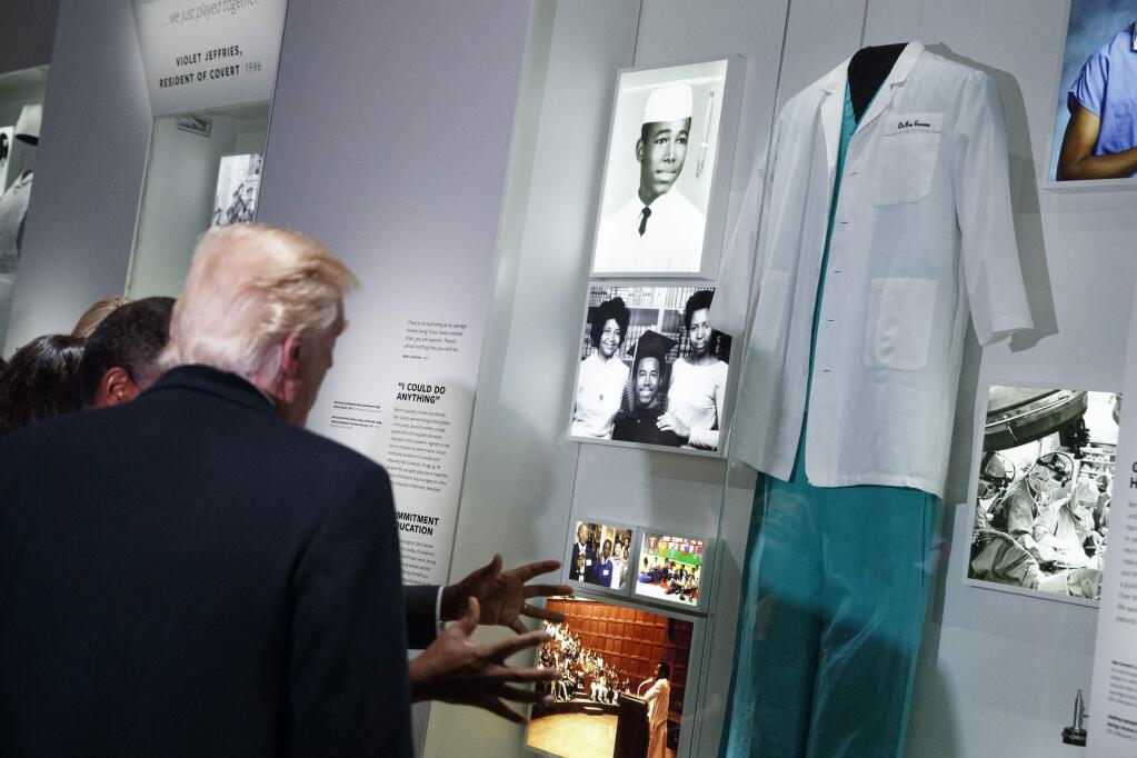 President Donald Trump looks at an exhibit of Dr. Ben Carson, his nominee for Housing and Urban Development secretary, during a tour of the National Museum of African American History and Culture, Tuesday, Feb. 21, 2017, in Washington. (AP Photo/Evan Vucci)