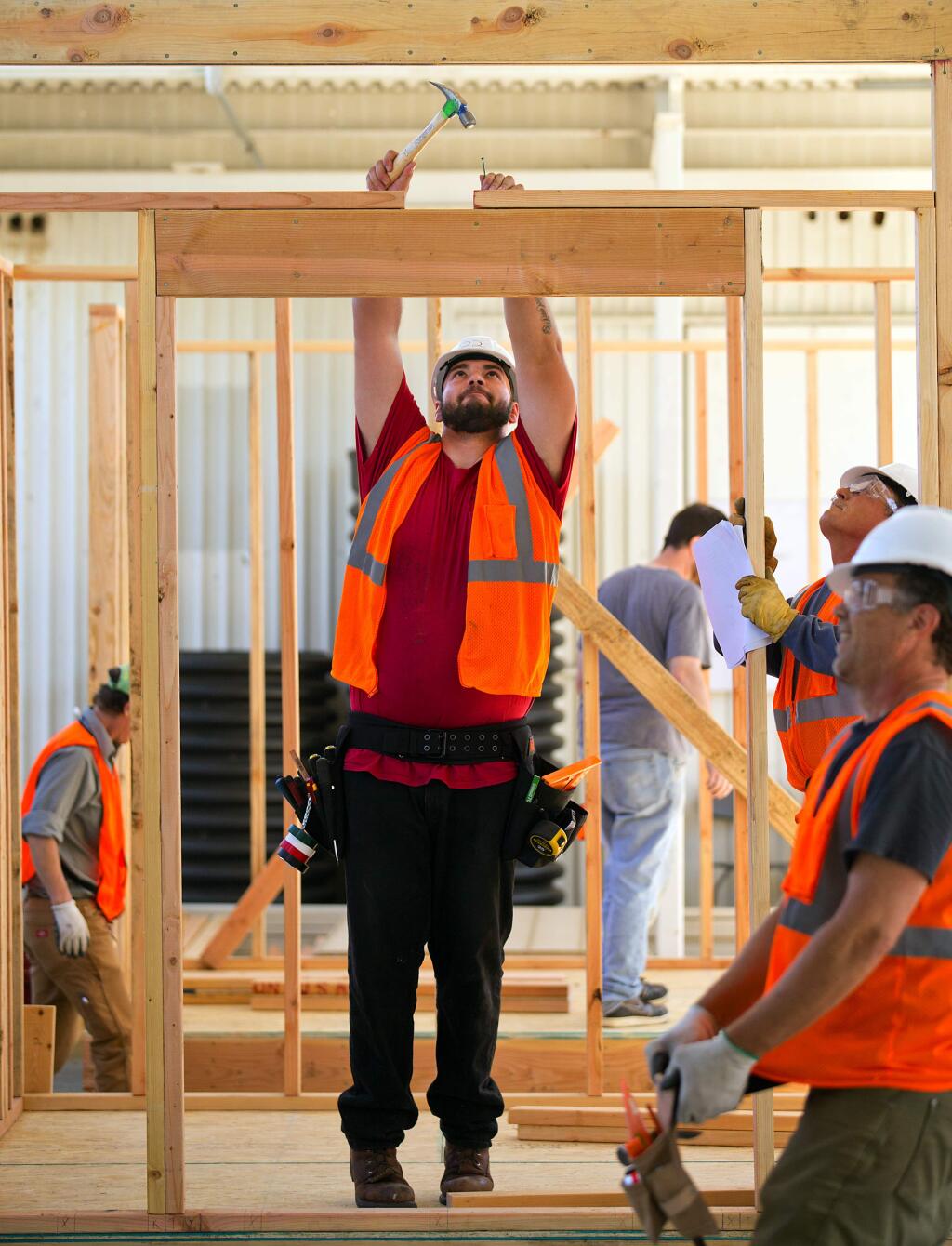 Kody Young stretches to nail a header for a doorway during a Sonoma County Adult Education basic construction class in Santa Rosa. (photo by John Burgess/The Press Democrat)