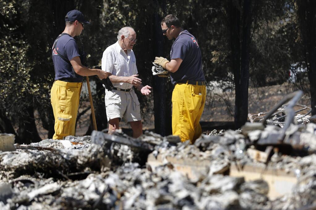 Cal Fire engineers Dustin Mattos, right, and Frank Rogers help homeowner Oliver Smith recover the broken pieces of an urn that had contained his late wife's ashes at his home on Sunday, September 20, 2015 in Hidden Valley Lake. (BETH SCHLANKER / The Press Democrat)