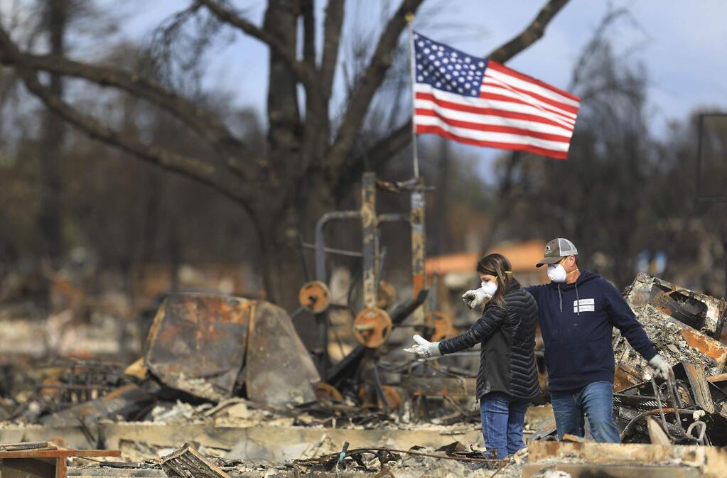 Linda and Jason Miller spot an item of interest in the burned home in Coffey Park, Friday Oct. 20, 2017 in Santa Rosa, Calif. Northern California residents who fled a wildfire in the dead of night with only minutes to spare returned to their neighborhoods Friday for the first time in nearly two weeks to see if anything was standing. (Kent Porter/The Press Democrat via AP)