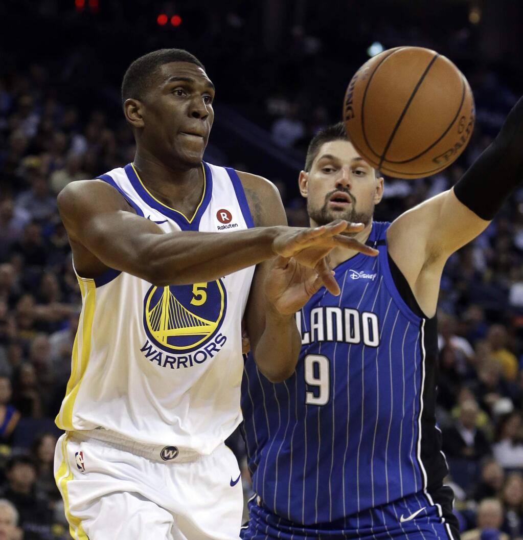 The Golden State Warriors' Kevon Looney, left, passes the ball away from the Orlando Magic's Nikola Vucevic during the second half Monday, Nov. 13, 2017, in Oakland. The Warriors won 110-100. (AP Photo/Ben Margot)
