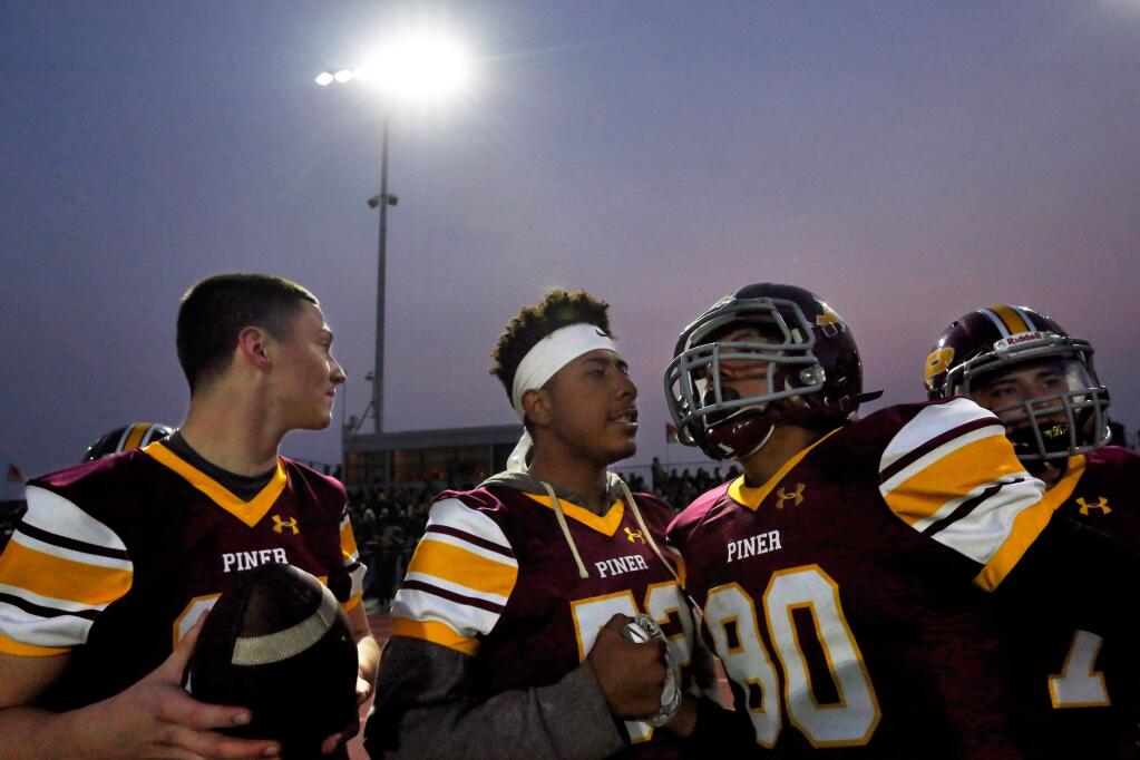 'Are you hungry?' Piner's De'Angelo Wallace, second from left, asks teammate Joseph Ruiz between plays during the first nighttime football game the Piner Prospectors played beneath the school's new field lights during their game against Novato High School, in Santa Rosa, California, on Friday, August 24, 2018. (Alvin Jornada / The Press Democrat)