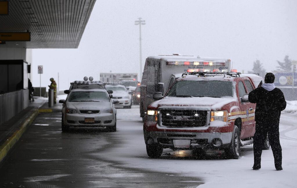 Emergency vehicles line up outside of a terminal at LaGuardia Airport in New York, Thursday, March 5, 2015. A plane from Atlanta skidded off a runway at the airport while landing Thursday, crashing through a chain-link fence and sending passengers saddled with bags and bundled up in heavy coats and scarves sliding down an inflated chute to safety on the snowy pavement. (AP Photo/Seth Wenig)