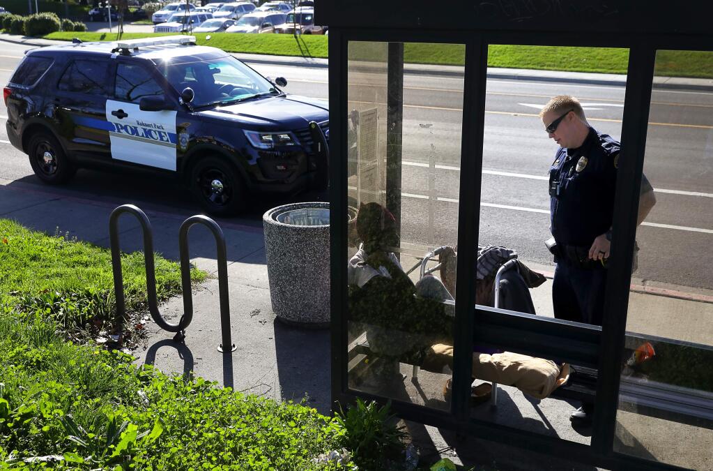 Rohnert Park Public Safety Officer David Wattson checks the welfare of a homeless woman at a bus stop in Rohnert Park on Thursday, February 1, 2018. (Christopher Chung/ The Press Democrat)