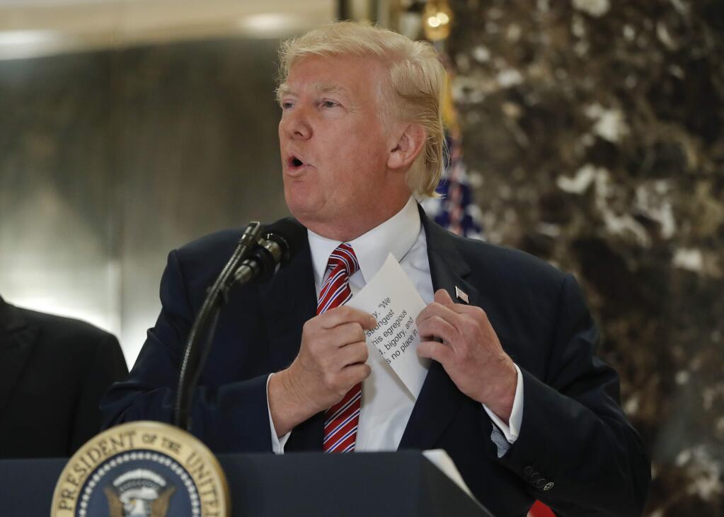 President Donald Trump reaching into his suit jacket to read a quote he made on Saturday regarding the events in Charlottesville, Va., as he speaks to the media in the lobby of Trump Tower, Tuesday, Aug. 15, 2017. (AP Photo/Pablo Martinez Monsivais)