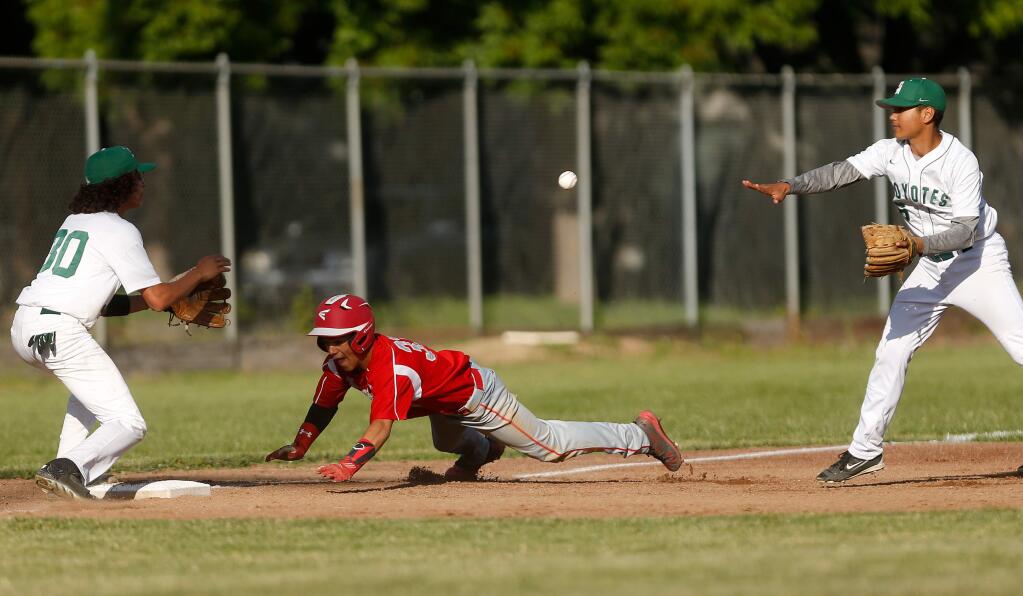 Upper Lake's Dre Santos, center, slides into third base after being caught in a rundown between Sonoma Academy's Nathan Becker, left, and Byron Spars during a varsity baseball game between Upper Lake and Sonoma Academy high schools, in Santa Rosa on Tuesday, May 9, 2017. Despite beating the throw back to third base, Santos would be called out because of running beyond the baseline. (Alvin Jornada / The Press Democrat)