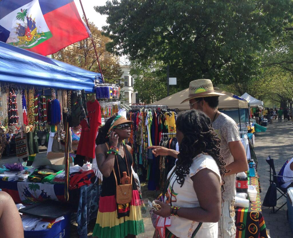 Ellie December, center, originally from Guyana, checks out fashions from a vendor along Eastern Parkway while waiting for the annual West Indian Day Parade to start in the Brooklyn borough of New York, Monday, Sept. 1, 2014. (AP Photo/Mark Lennihan)