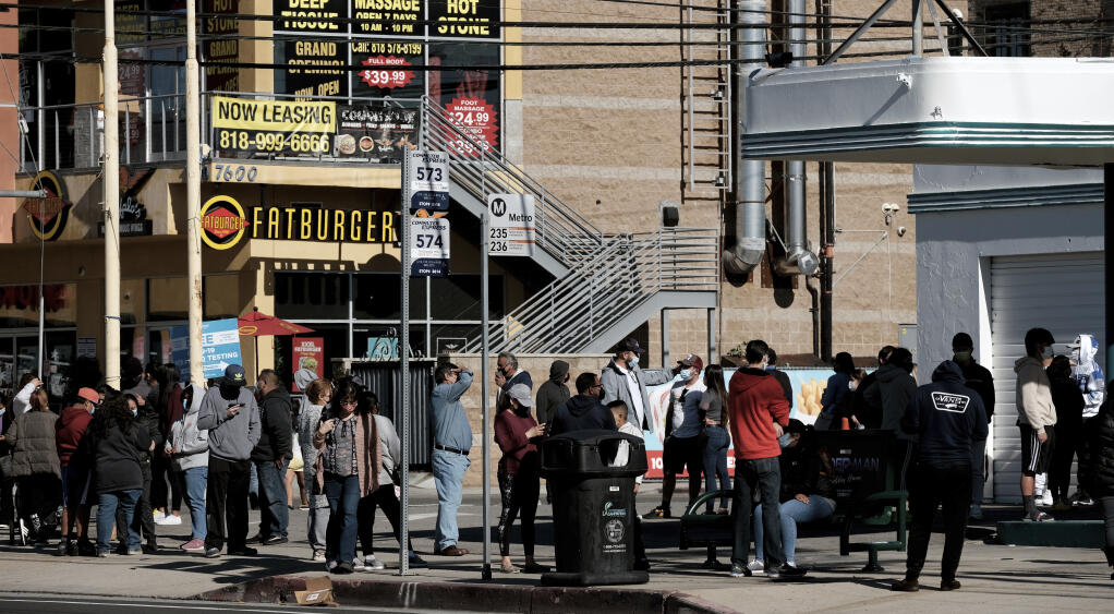 People line up for a free COVID-19 rapid test at a gas station in the Reseda section of Los Angeles on Sunday, Dec. 26, 2021, as California braces for a post-holiday virus surge. (AP Photo/Richard Vogel)