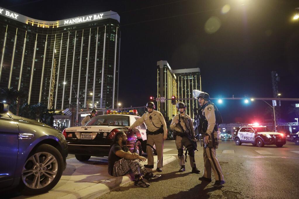 FILE - In this Sunday, Oct. 1, 2017 file photo, police officers stand at the scene of a mass shooting near the Mandalay Bay resort and casino on the Las Vegas Strip, in Las Vegas. A revised chronology given by investigators for the Las Vegas massacre is intensifying pressure for police to explain how quickly they responded to what would become the deadliest mass shooting in modern U.S. history. (AP Photo/John Locher, File)