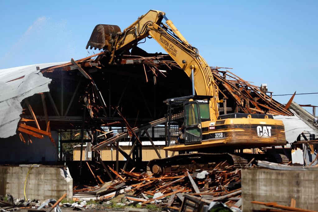An excavator pulls down part of the roof that was once covered the repair shop of the Pellini Chevrolet car dealership in Sebastopol, California on Wednesday, March 16, 2016. (Alvin Jornada / The Press Democrat)