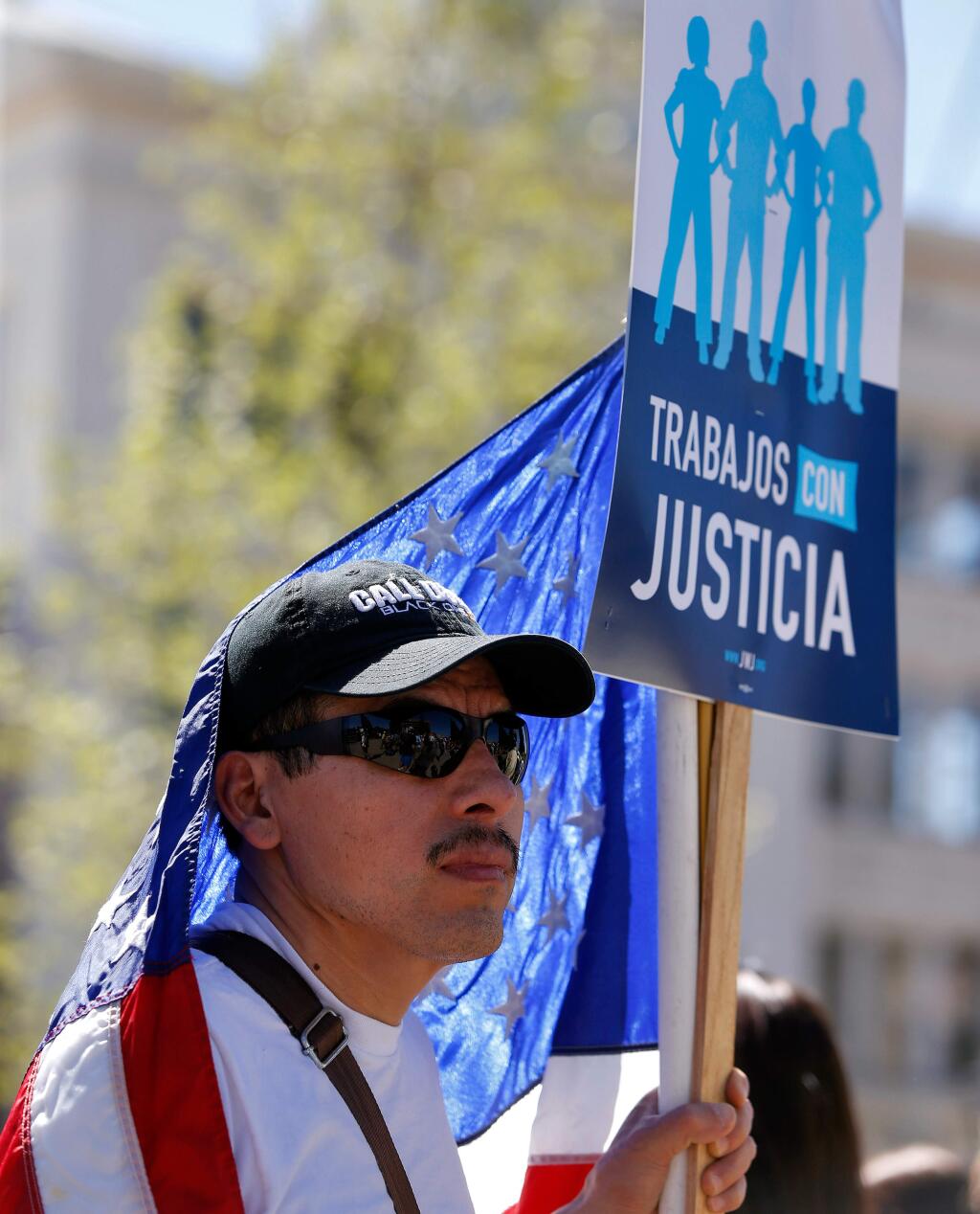 Joe Jimenez's American flag wraps around his shoulders during a march for jobs, justice, and the climate that ended at Old Courthouse Square, in Santa Rosa, California, on Saturday, April 29, 2017. (Alvin Jornada / The Press Democrat)