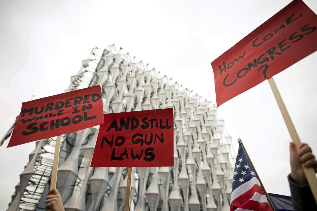 Protesters hold up signs outside the US Embassy in London, Saturday March 24, 2018, in solidarity with the “March for Our Lives” protest against gun violence. (Stefan Rousseau/PA via AP)