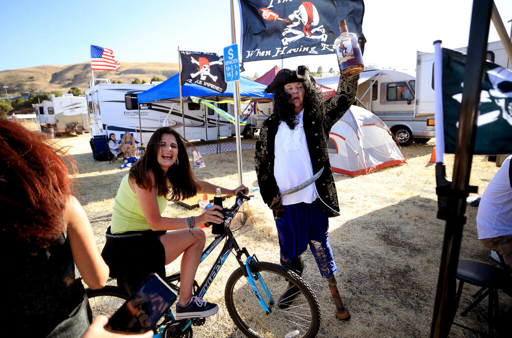 Chris Paulsen of Sacramento plays the part of a pirate, much to the humor of Cindy Watson of Georgetown, as NASCAR fans return to the 50-acre lot at Sonoma Raceway, Thursday, June 3, 2021 in Sonoma.  Paulsen's compound is the site of Captain Ron's Bar;  the group went with a pirate theme.   (Kent Porter / The Press Democrat)
