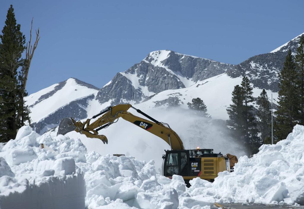 In this photo taken Tuesday, June 6, 2017, a Caltrans excavator removes snow from Highway 120 near Yosemite National Park, Calif. This year's heavy snowfall has crews working to clear Highway 120 as summer approaches; the only road through Yosemite that connects the Central Valley on the west side with the Owens Valley on the east side of the Sierra Nevada. (AP Photo/Rich Pedroncelli)