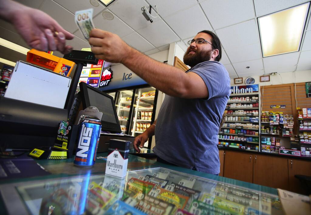 Aman Gill sells a pack of cigarettes to a customer at his family's Fast Lane gas station in Healdsburg, on Tuesday, June 30, 2015. The age limit to purchase cigarettes and tobacco products in Healdsburg has been raised to 21.(Christopher Chung/ The Press Democrat)