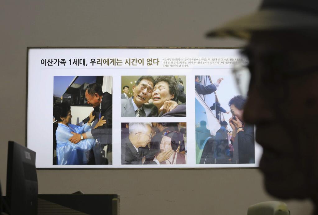 Photos showing the reunion of family members from North and South Korea are displayed as South Korean Yoo Gi-jin, 93, talks with a Red Cross official to fill out application forms to reunite with his family members living in North Korea, at the headquarters of the Korea Red Cross in Seoul, South Korea, Friday, June 22, 2018. North and South Korean officials met Friday for talks on resuming reunions of families divided by the 1950-53 Korean War as the rivals boost reconciliation amid a diplomatic push to resolve the North Korean nuclear crisis. The signs on the photos read: '1st generation of separated families. We do not have time.' (AP Photo/Ahn Young-joon)
