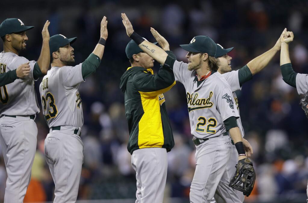 Oakland Athletics right fielder Josh Reddick (22) high fives teammates after their 5-3 win over the Detroit Tigers in a game, Tuesday, June 2, 2015, in Detroit. (AP Photo/Carlos Osorio)