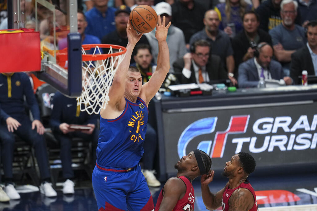 Denver Nuggets center Nikola Jokic, left, passes the ball next to Miami Heat forward Jimmy Butler, center, during the first half of Game 1 of the NBA Finals, Thursday, June 1, 2023, in Denver. (Jack Dempsey / ASSOCIATED PRESS)