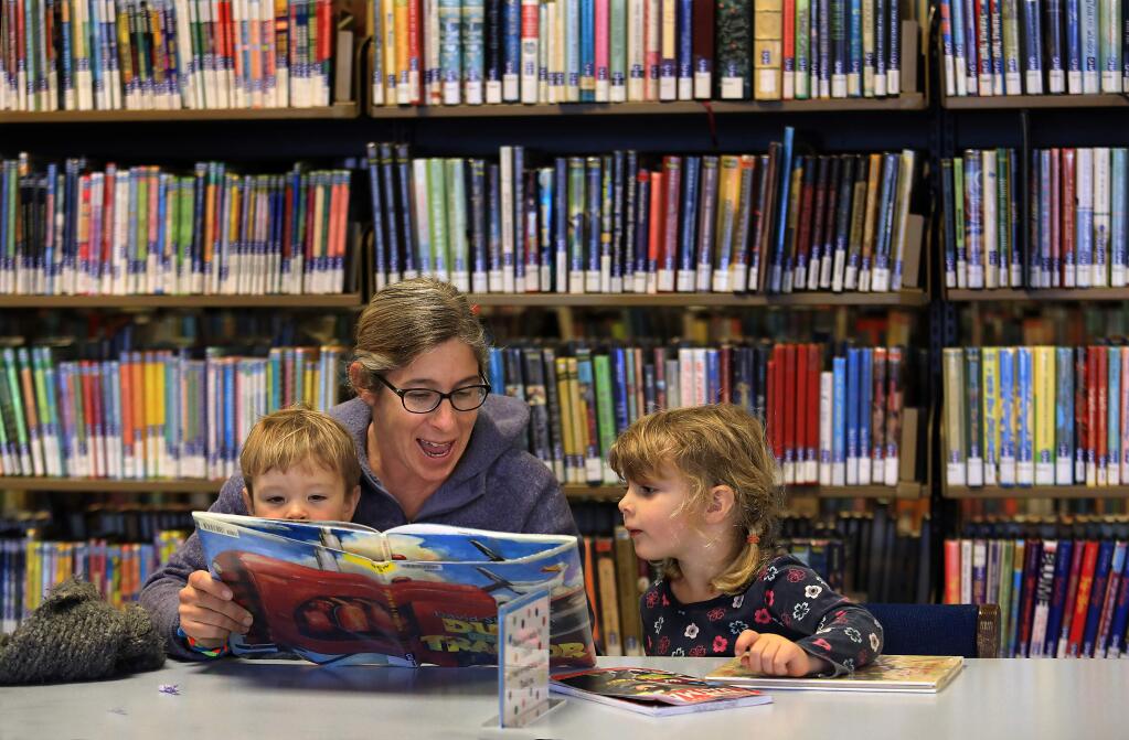 Sarah Tuckman reads with Dylan Beirne, 21 months, and his sister Aria, 3, in the children's section at the Sonoma County Central Library in Santa Rosa on Tuesday, January 3, 2017. (John Burgess/The Press Democrat)