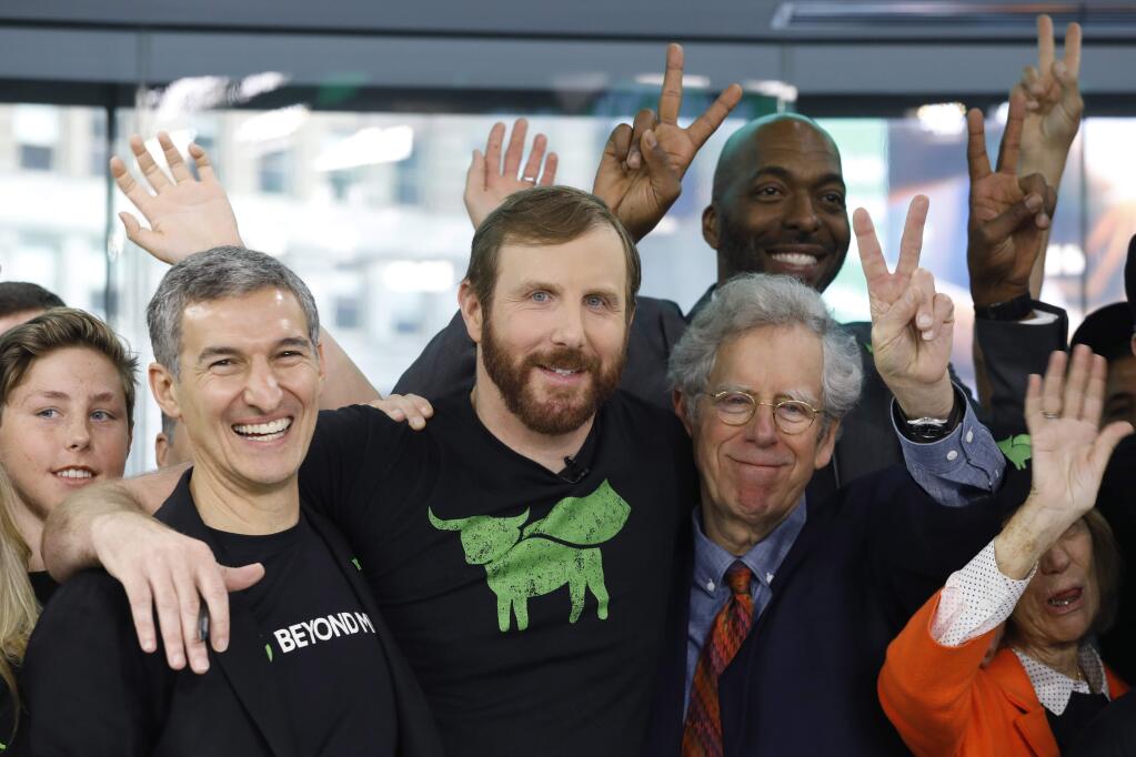 Ethan Brown, center, CEO of Beyond Meat, attends the Opening Bell ceremony to celebrate the company's IPO at Nasdaq, Thursday, May 2, 2019 in New York. California-based Beyond Meat makes burgers and sausages out of pea protein and other ingredients. (AP Photo/Mark Lennihan).