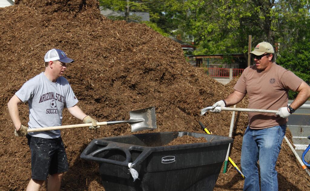 Joel Green,left, and Tony Moll fill a cart with mulch.