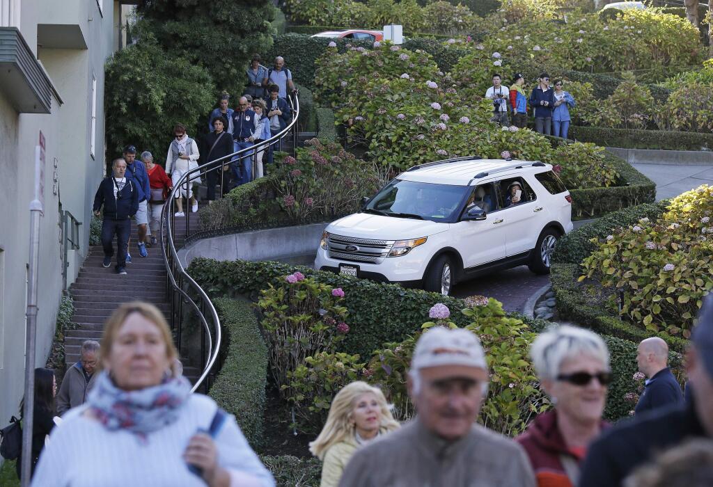 FILE - In this Sept. 21, 2016, file photo, tourists make their way down Lombard Street, also known as the 'most crooked street' in San Francisco. A San Francisco supervisor is calling for a toll on the famously crooked street that has become too popular with tourists and creates headaches for residents. (AP Photo/Eric Risberg, File)