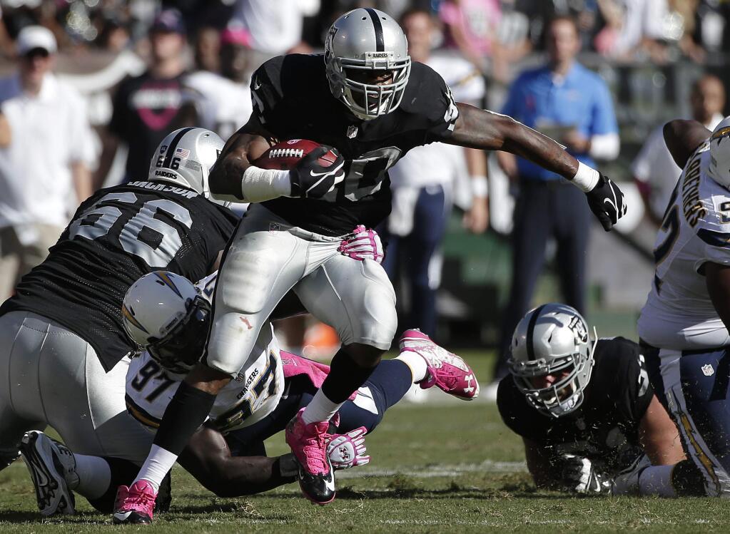 Oakland Raiders running back Darren McFadden (20) runs through a tackle attempt by San Diego Chargers outside linebacker Jeremiah Attaochu (97) during the fourth quarter of an NFL football game in Oakland Sunday, Oct. 12, 2014. (AP Photo/Marcio Jose Sanchez)