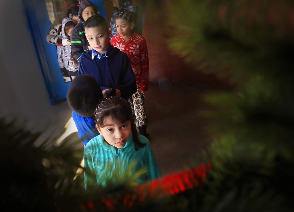 Kayla Ruiz, 6, front, waits patiently with her brother Jose Ruiz, 9, and friend Donna Valaivia, in red, for doors to be opened at St. Vincent DePaul for a gift giveaway in Santa Rosa, Friday Dec. 25, 2015. (Kent Porter / Press Democrat) 2015
