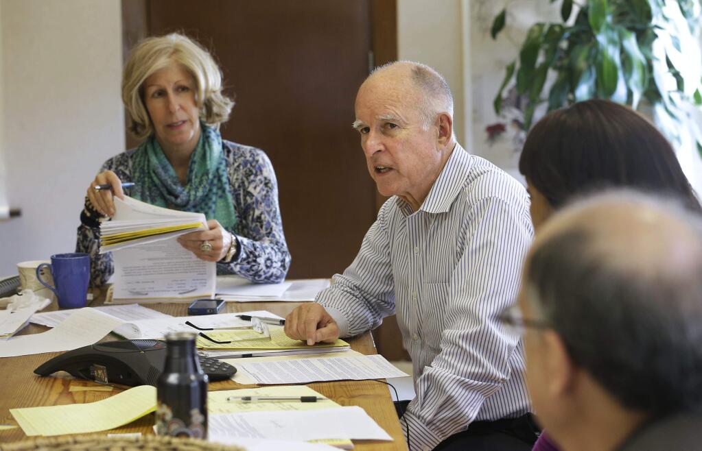 Gov. Jerry Brown discusses a bill while meeting with advisers at his Capitol office in Sacramento, Calif., Monday, Sept. 29, 2014. Brown has until midnight Sept. 30 to sign or veto hundreds of bills that were approved in the finals weeks of the legislative session. At left is advisor Nancy McFadden. (AP Photo/Rich Pedroncelli)