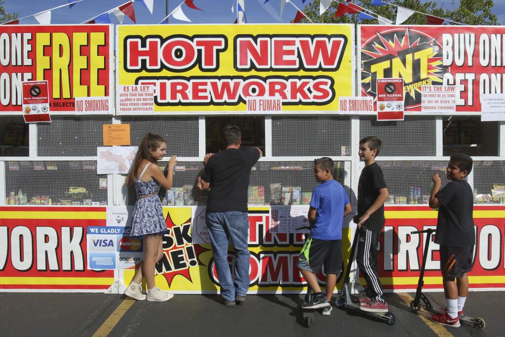 From Left, Amber Rahman, 13, her dad Kevin Rahman, Josue Ramales, 11, Nico Rahman ,11, and Daniel Hernandez shop for fireworks at the North Coast Football Club's booth in the Petaluma Plaza North Shopping Center on N Mcdowell blvd. on Tuesday, June 23, 2015. (SCOTT MANCHESTER/ARGUS-COURIER STAFF)