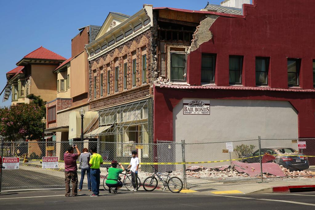 Residents and tourists stop to take pictures of earthquake-damaged buildings along Brown Street in downtown Napa on Thursday, Aug. 28, 2014. The buildings had not been retrofitted to comply with a 2006 ordinance. (Conner Jay/The Press Democrat)