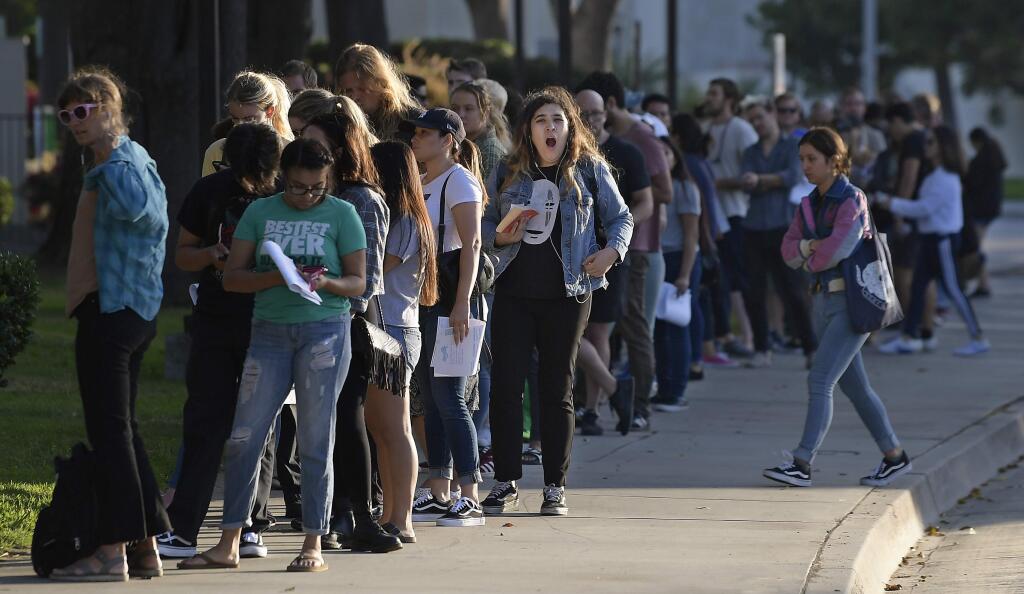 A woman yawns as she waits in a long line to register and vote at the Los Angeles County Registrar's office Tuesday, Nov. 6, 2018, in Los Angeles. A spokesman with the registrar's office says the line at its headquarters in Norwalk is wrapping around the building and that wait times were at about two hours Tuesday. (AP Photo/Mark J. Terrill)