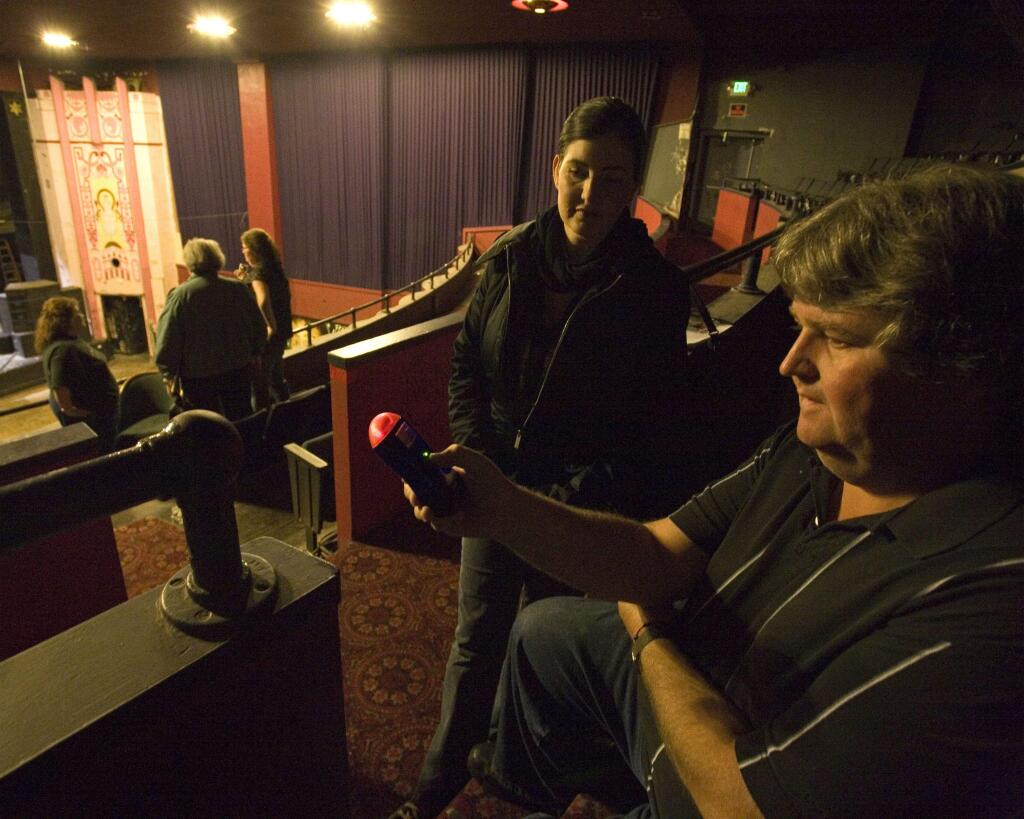 Dave Henderson and Kim Malone, both with the Pursuit of Paranormal Studies, use a meter to detect changes in electricity inside the Phoenix Theater. Photo by Terry Hankins.