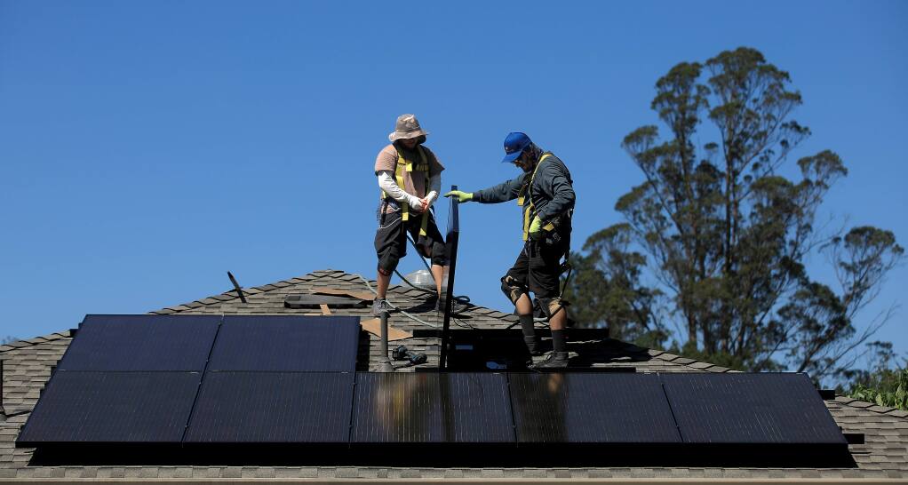 Mateo Sheerin, left, and Justin Hiner of Synergy Solar prepare to fish off the south facing aspect of a solar panel installation, Thursday, Sept. 12, 2019 in Sebastopol. (Kent Porter / The Press Democrat) 2019