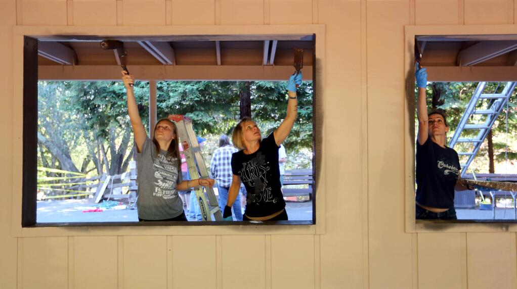 Friends and family of members of Boy Scouts Troop 121, from left to right, Grace Murdock, 13, Robin Murdock, and Christina Cartier paint the Howarth Park Train Station in Santa Rosa, Saturday, November 8, 2014. (Crista Jeremiason / The Press Democrat)