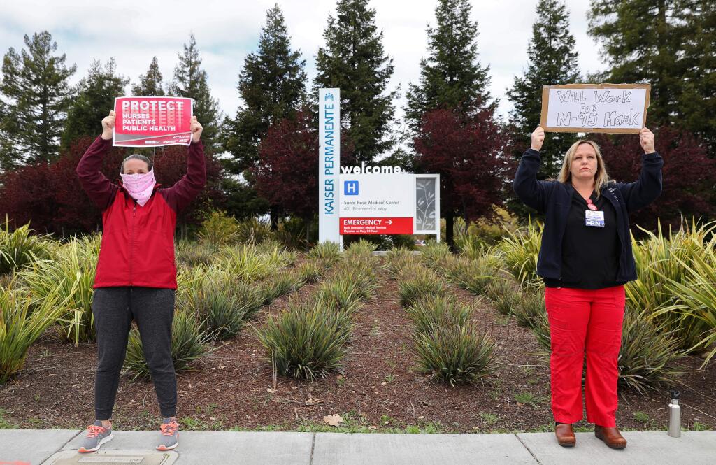Registered nurses Melissa L., left, who did not want to provide her last name, and Chelsea Carrera protest the shortage of personal protective equipment supplied to public health workers at Kaiser Permanente, in Santa Rosa on Monday, March 23, 2020. (Christopher Chung/ The Press Democrat)