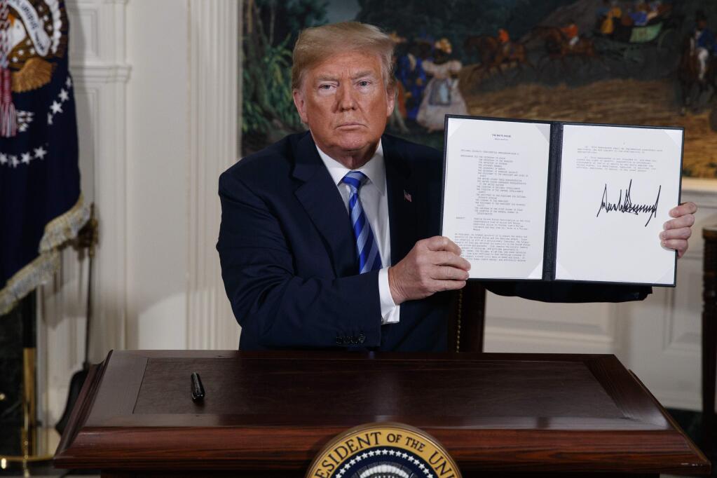 FILE - In this May 8, 2018 file photo President Donald Trump shows a signed Presidential Memorandum after delivering a statement on the Iran nuclear deal from the Diplomatic Reception Room of the White House. Iranian President Hassan Rouhani is reportedly set to announce Wednesday, May 8, 2019, ways the Islamic Republic will react to continued U.S. pressure after President Donald Trump pulled America from Tehran‚Äôs nuclear deal with world powers. (AP Photo/Evan Vucci, File)