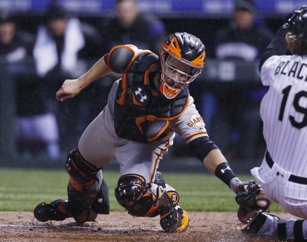 San Francisco Giants catcher Buster Posey, left, turns to apply a late tag as the Colorado Rockies' Charlie Blackmon slides safely across home plate to score on his two-run inside-the-park home run in the fourth inning Friday, April 21, 2017, in Denver. (AP Photo/David Zalubowski)