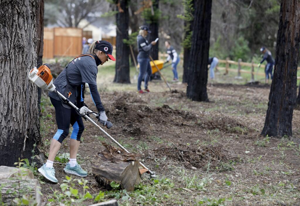 Mirinda Carfrae, a professional triathlete and an Ironman Triathlon world champion, joins with volunteers organized by the IRONMAN Foundation to clear vegetation along Mark West Creek near homes being rebuilt on Pacific Heights Drive in Larkfield-Wikiup on Thursday, May 9, 2019. (BETH SCHLANKER/ The Press Democrat)